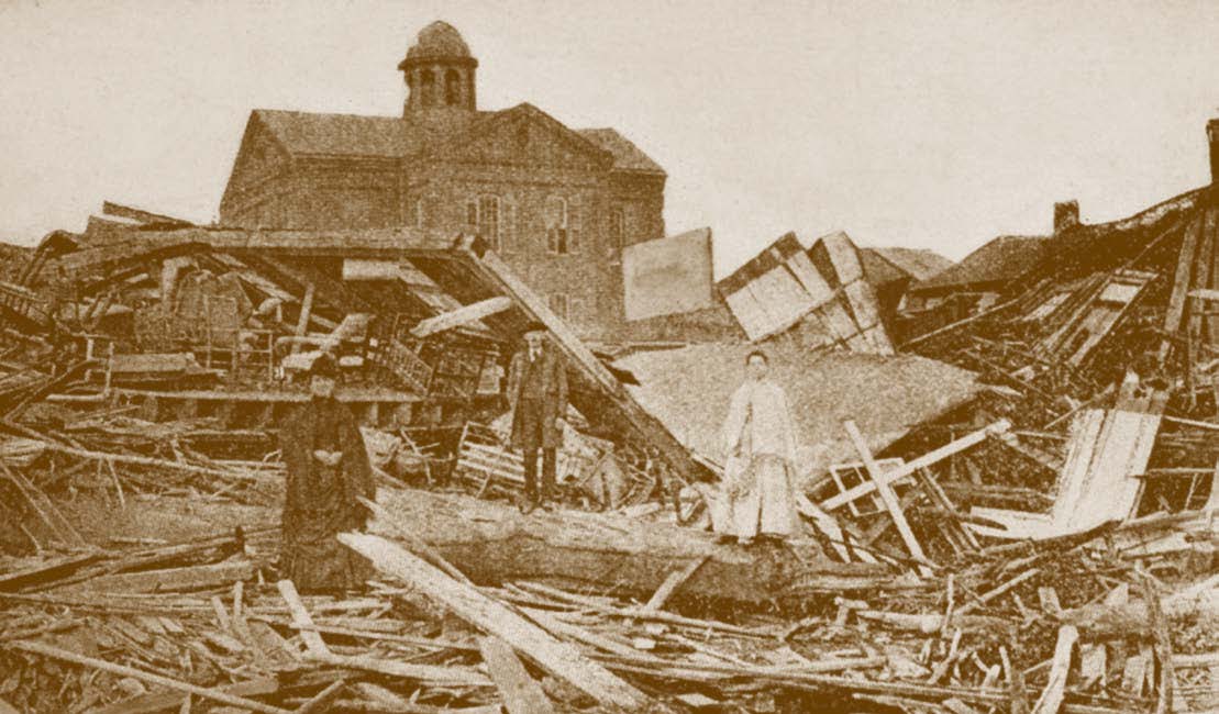 People standing among destroyed homes in 1900.